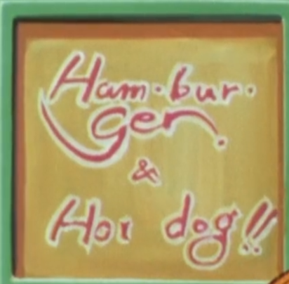 A cropped anime screenshot of a yellow sign with a green frame. In red text, it reads 'Ham Bur Ger' with dots after every syllable, and 'Ger' is on a different line. Below, there's an ampersand. The next line reads 'Hot dog' with a slightly awkward amount of space between the words, and two exclamation points.